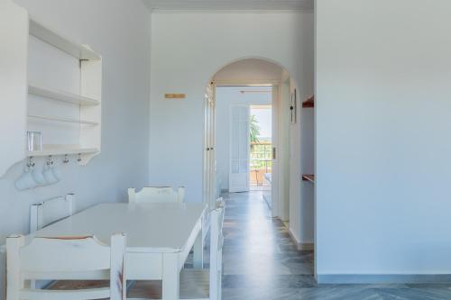een witte kamer met een tafel en stoelen bij ILENA HOTEL in Acharavi