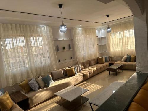 Villa famillial avec piscine Founty في أغادير: غرفة معيشة كبيرة مع أريكة كبيرة ونوافذ