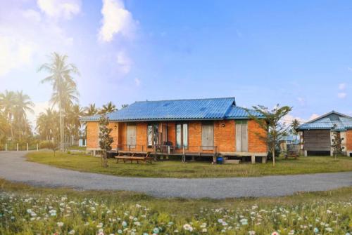 una casa con techo azul en un campo en Sekepeng Penarek, en Kampung Penarik