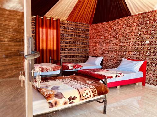 una habitación con 3 camas en una tienda de campaña en Salameh's Bedouin Camp, en Wadi Rum