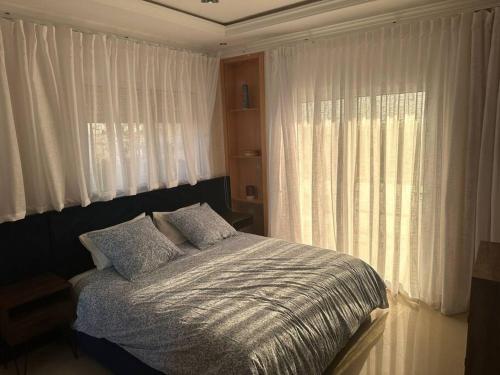 Schlafzimmer mit einem Bett und einem Fenster mit Vorhängen in der Unterkunft Villa famillial avec piscine Founty in Agadir