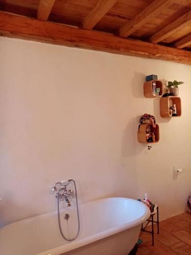 La salle de bains est pourvue d'une baignoire blanche et d'un plafond. dans l'établissement Grande maison cévenole à la décoration soignée, à Notre-Dame-de-la-Rouvière