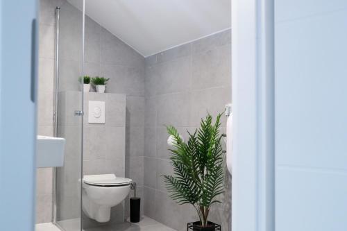 a bathroom with a toilet and a plant in it at Imperium Rooms Zagreb Airport in Velika Gorica