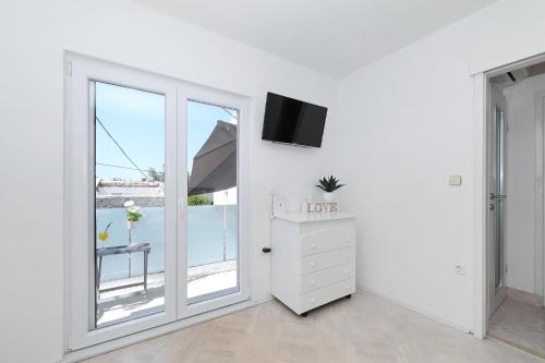 a white room with a large window and a dresser at Holiday Home Maria one minute from -Beach in Zadar