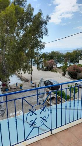 a blue metal fence with a view of a parking lot at Στούντιο με θέα τη θάλασσα in Itea
