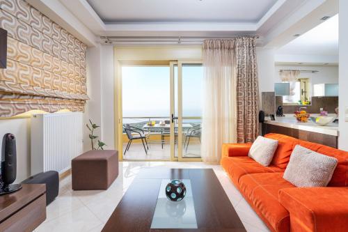 a living room with an orange couch and a table at Artemisia Sunset View in Sitia
