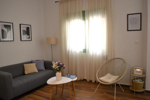 een woonkamer met een bank, een tafel en een raam bij Yannis Guest House in Aegina Town