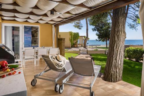 a patio with chairs and a table and a tree at Istrian Villas Plava Laguna in Umag