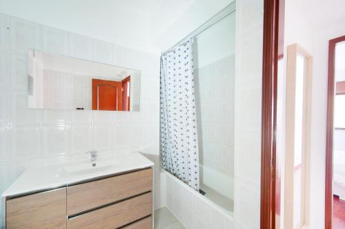 a white bathroom with a sink and a shower at Amazing Apartments in Agualva