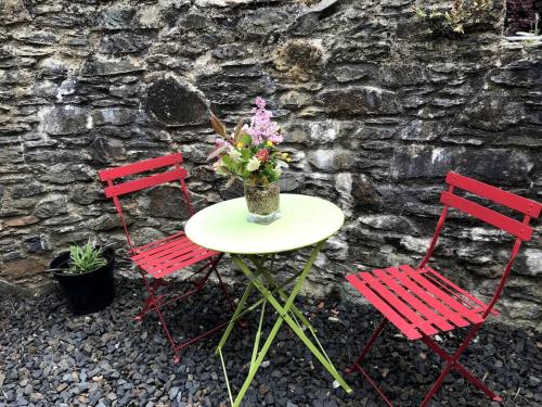 two red chairs and a table with a vase of flowers at Namastay at Longacre in Woodland