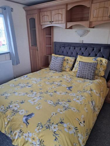 a bed with a yellow comforter with birds on it at Golden sands ingoldmells in Skegness
