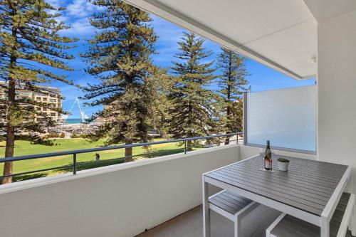 a balcony with a table and a window at Sea and Park Deluxe Glenelg in Glenelg