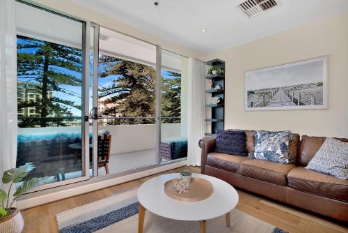 a living room with a couch and a table at Sea and Park Deluxe Glenelg in Glenelg
