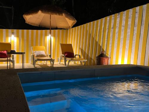 a pool with two chairs and a table and an umbrella at Emiliadourohouse in Marco de Canaveses