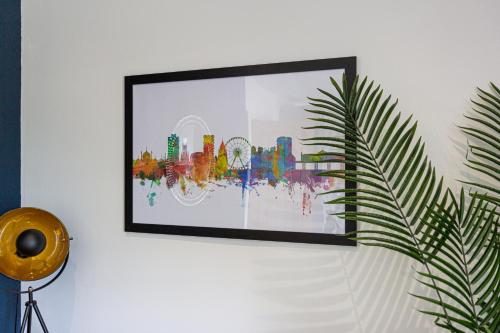 a picture hanging on a white wall with a plant at Albion at the Level - 2 BD Flat in Brighton & Hove