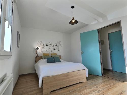 een slaapkamer met een bed met witte lakens en blauwe kussens bij Tout Inclus - Plein Centre - Netflix - Moontown in Lunéville