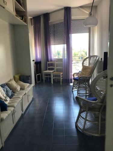 - un salon avec des chaises, un canapé et une fenêtre dans l'établissement Appartamento panoramico centro, à Riccione