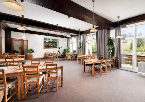 a restaurant with wooden tables and chairs and windows at Hotel Liptov in Demanovska Dolina