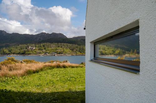 a window on a building with a view of a lake at Plockton Shoreside House in Plockton
