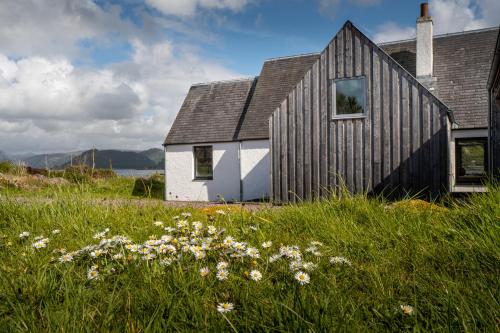 a black and white house with a field of flowers at Plockton Shoreside House in Plockton