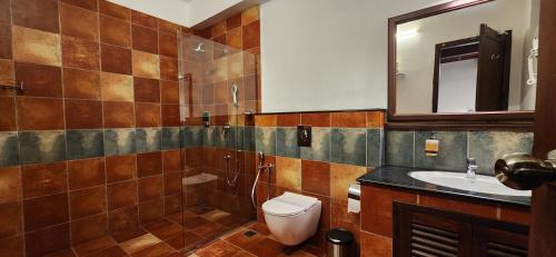 a bathroom with a toilet and a sink and a mirror at Kumarakom Tharavadu - A Heritage Hotel, Kumarakom in Kumarakom