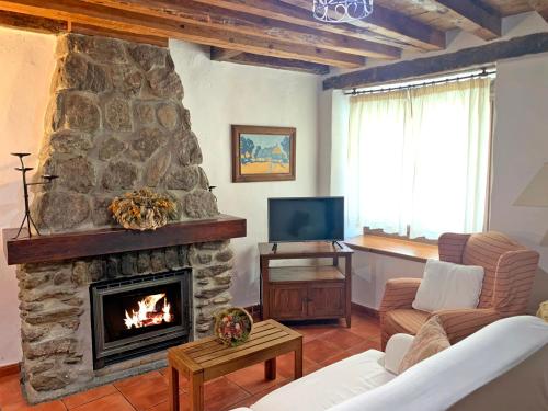 uma sala de estar com uma grande lareira de pedra em Casa rural Álamo - Valle de El Paular em Rascafría