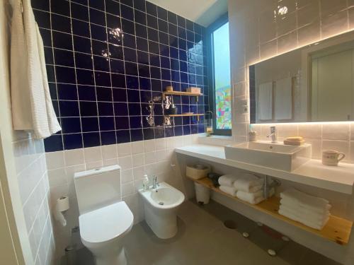 a blue tiled bathroom with a toilet and a sink at CaLoura 76 in Lagoa