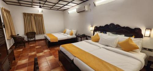 a hotel room with two beds and a chair at Kumarakom Tharavadu - A Heritage Hotel, Kumarakom in Kumarakom