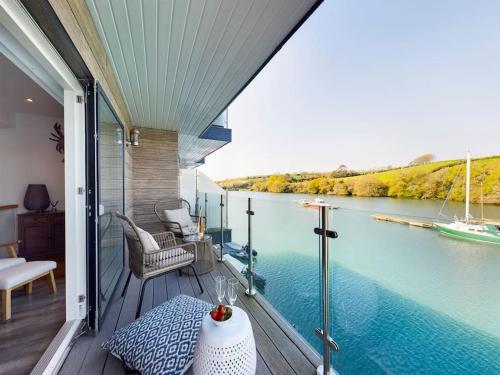 a balcony with a view of a river with a boat at 1 The Boatyard - Water fronted, town location & parking for 2 cars in Kingsbridge