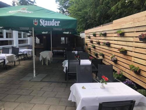 a restaurant with tables and a green umbrella at Hotel-Restaurant Schmachtenbergshof in Essen
