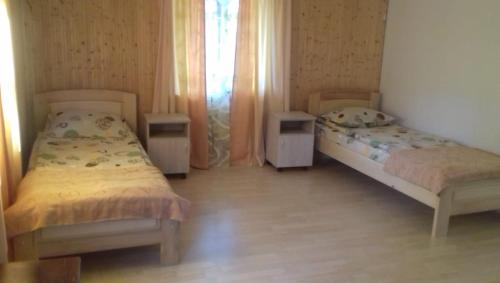 sypialnia z 2 łóżkami, 2 stołami i oknem w obiekcie Guesthouse Mevele w mieście Omalo