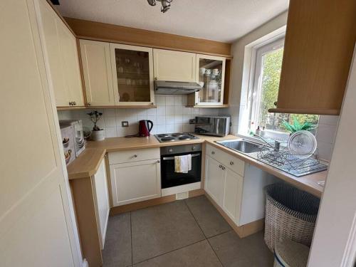 a small kitchen with white cabinets and a sink at Chic 3 Bed in the heart of Chiswick in London