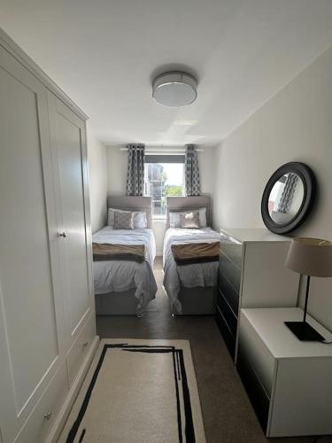 a small bedroom with two beds and a mirror at Chic 3 Bed in the heart of Chiswick in London