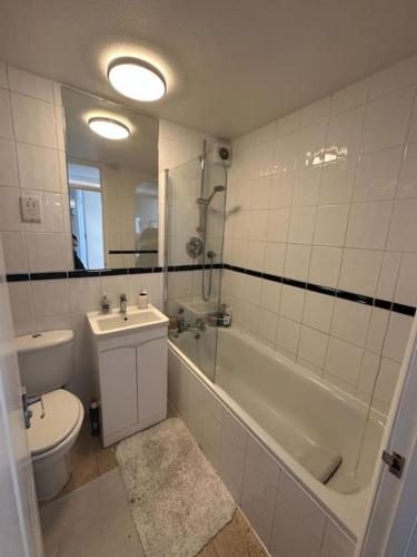 a bathroom with a toilet and a tub and a sink at Chic 3 Bed in the heart of Chiswick in London