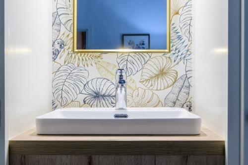 een badkamer met een witte wastafel en een spiegel bij La Tour Des Remparts in Rochemaure
