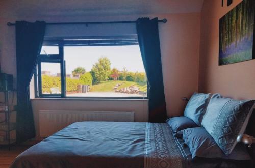 1 dormitorio con cama y ventana grande en Benbulben View F91YN96, en Sligo