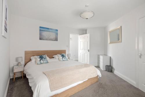 a white bedroom with a large bed with blue pillows at Beach Front House in Walton-on-the-Naze