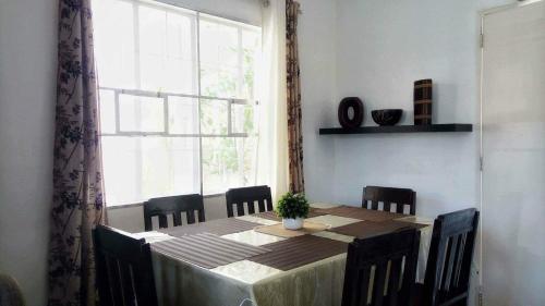 uma mesa de jantar com cadeiras e uma grande janela em HMH Family Villa in Mexico, Pampanga em Mexico