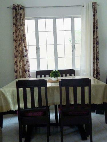 uma mesa de jantar com 2 cadeiras e uma janela em HMH Family Villa in Mexico, Pampanga em Mexico
