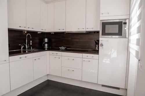 a white kitchen with white cabinets and a refrigerator at Vakantiewoning op het sluisplateau 23 Wemeldinge in Wemeldinge