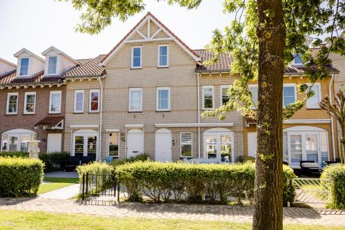 a large house with a tree in front of it at Vakantiewoning op het sluisplateau 23 Wemeldinge in Wemeldinge
