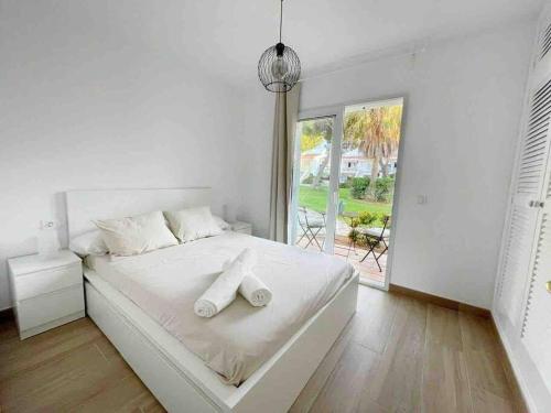ein weißes Schlafzimmer mit einem Bett mit zwei Handtüchern darauf in der Unterkunft Apartamento Lia con piscina en Port Addaia in Port d'Addaia