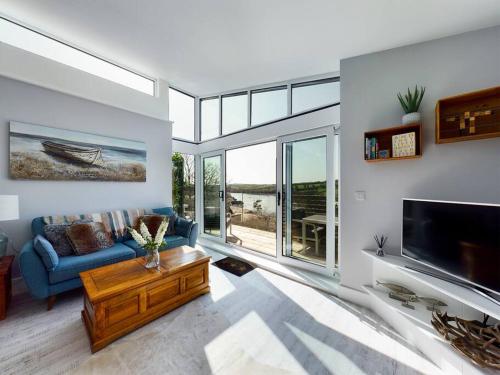a living room with a blue couch and a tv at Paddlers View - Luxurious 2 bed, hot tub. Town centre, water views in Kingsbridge
