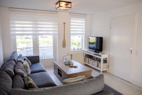 a living room with a couch and a tv at Vakantiewoning op het sluisplateau 23 Wemeldinge in Wemeldinge
