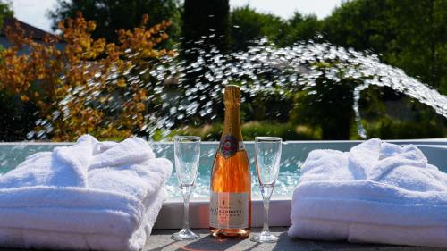 a bottle of champagne sitting on a table with glasses at DOMAINE DES PIERRES PRECIEUSES - Grand Standing - 2 à 15 pers - Chic - Spa - Détente - Massages - Bien-être - 30' Bordeaux in Gauriaguet