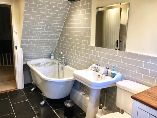 een badkamer met een bad, een wastafel en een toilet bij Honeysuckle Cottage in Longnor