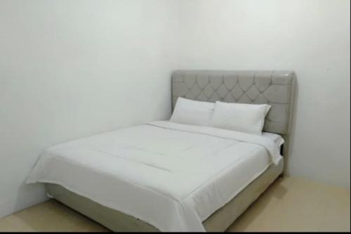 uma cama branca com lençóis e almofadas brancos em SPOT ON 92616 As-sakinah Syariah em Medan