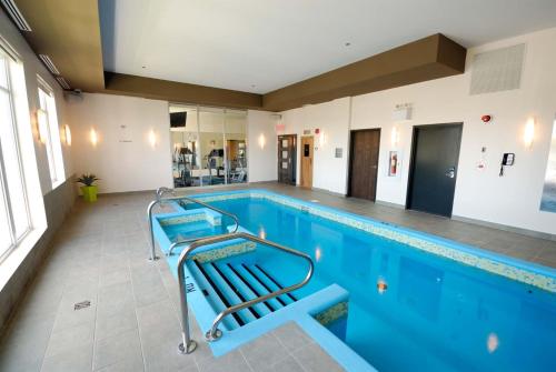 a swimming pool with two blue chairs in it at Imperia Hôtel et Suites Terrebonne in Terrebonne