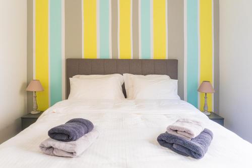 1 dormitorio con 1 cama con toallas en Bright 2bd apt, garden view & parking - Glyfada, en Atenas