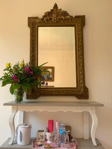 a mirror on top of a table with flowers at Le chant des oiseaux in Viry